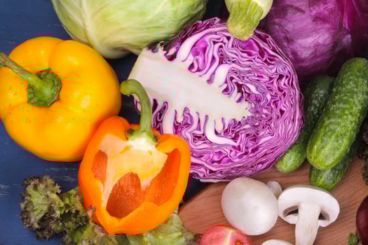 Many different vegetables include cabbage, zucchini, tomatoes, peppers, mushrooms and cucumbers on a blue wooden background. top view photo