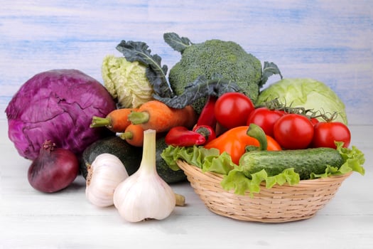 Many different vegetables include beets, cabbage, zucchini, carrots, tomatoes, peppers, onions, garlic, and cucumbers and lettuce on a white and blue wooden background. photo