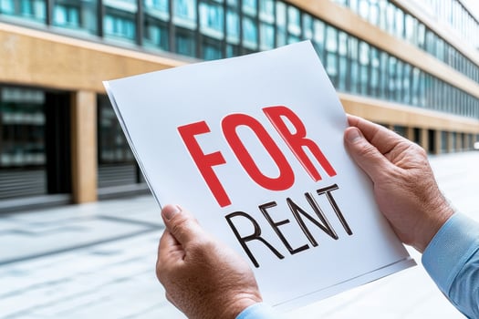 For rent sign held in front of modern office building photo
