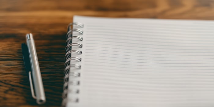 Blank spiral notebook and pen on wooden desk background photo