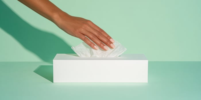 Minimalist flat lay of a white tissue box on green background for hygiene and cleanliness photo