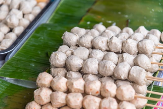 A bunch of meatballs on sticks with a banana leaf photo