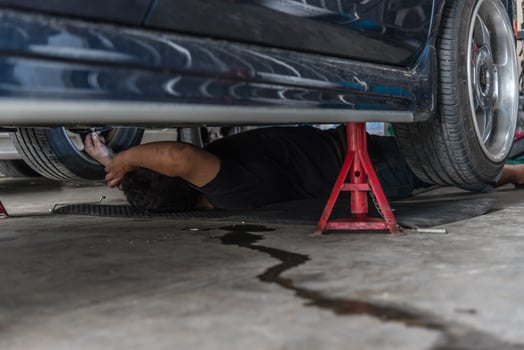 A man laying on the ground under a car photo