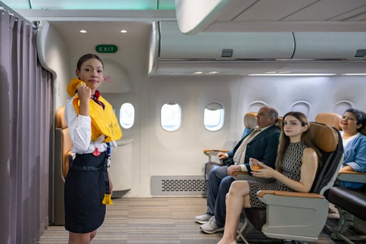 African flight attendant is demonstrating safety procedure using life jacket before taking off in airplane for cabin crew and airline business photo