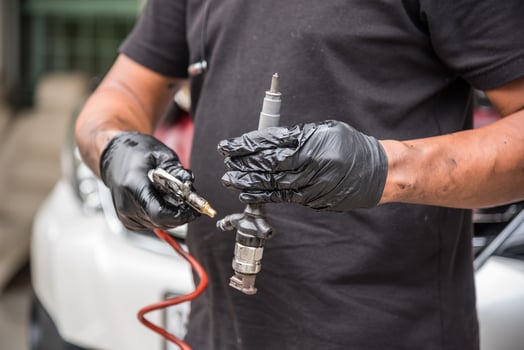 A man in black gloves holding a tool and a car photo