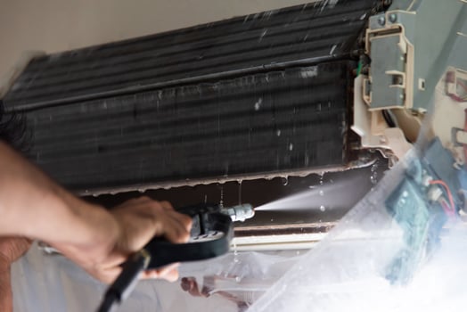 A man is using a spray gun to clean an air conditioner photo