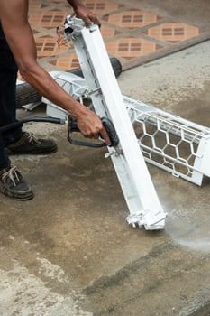 A man is using a hose to clean a white object photo