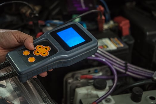A person holding an electronic device that is connected to a car photo
