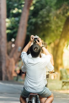 A man and woman riding a bicycle with a camera photo