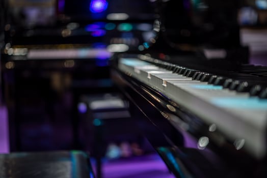 A piano is shown in a purple and black room photo