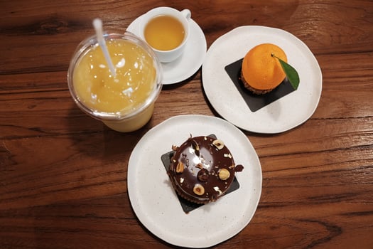 Homemade fresh Chocolate Hazelnut cake with orange cake and cream on chocolate Hazelnut and orange juice with a cup of hot tea on wooden table. top view photo