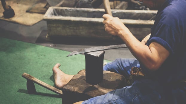 A man is working on a piece of metal with an anvil photo