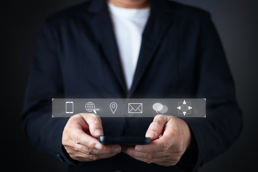 A businessman in a suit holds a smartphone with floating icons for contact options, including phone, email, location, chat, and global web, emphasizing accessibility and connectivity for contact us. photo