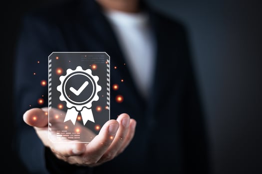 A businessman presents a glowing digital certificate icon with a checkmark and ribbon, symbolizing quality assurance, certification, and trustworthiness in a dark, futuristic environment photo