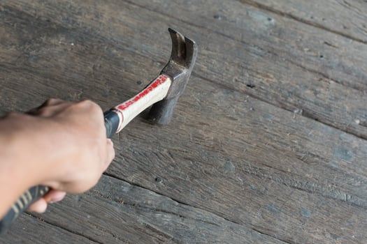 A person holding a hammer on a wooden floor photo