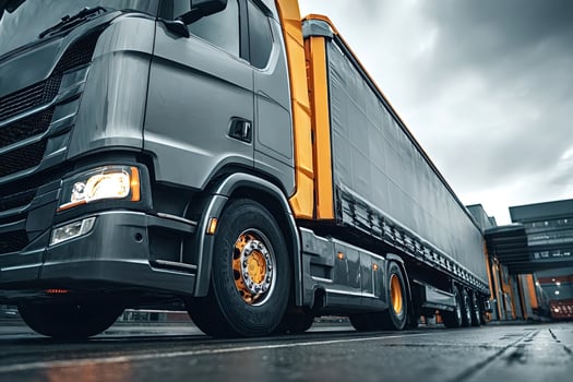 Grey and yellow semi truck leaving loading docks on cloudy day photo