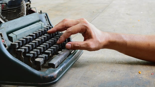 A person's hand is on top of an old typewriter photo