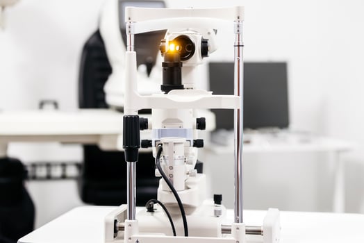 Ophthalmic examination equipment featuring a slit lamp with illuminated lens, positioned on a clinical table in a modern eye care facility, showcasing advanced diagnostic technology for eye photo