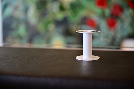 Empty white plastic thread spool on leather surface photo