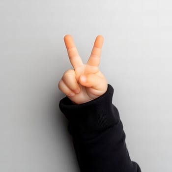 Close up of child hand showing peace sign with index and middle fingers symbolizing peace victory or number two photo