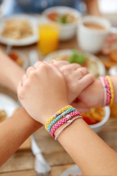 Friends showing friendship bracelets during lunch photo