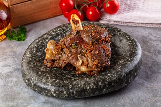 A piece of meat on a stone plate with tomatoes and herbs photo