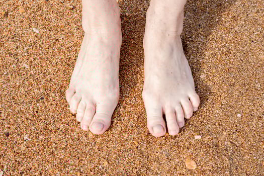 Bare feet stand on a sandy beach capturing a simple moment of relaxation and unity with nature photo