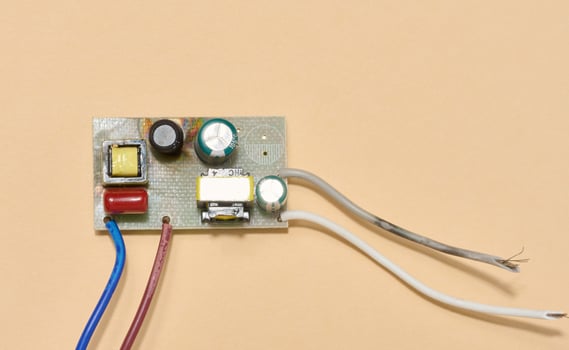 Electronic board with wires located on a beige background. Top view photo