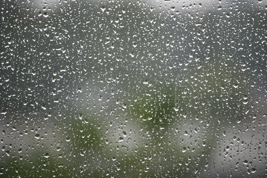 Raindrops on Glass Window with Natural Blurred Background Outdoors photo