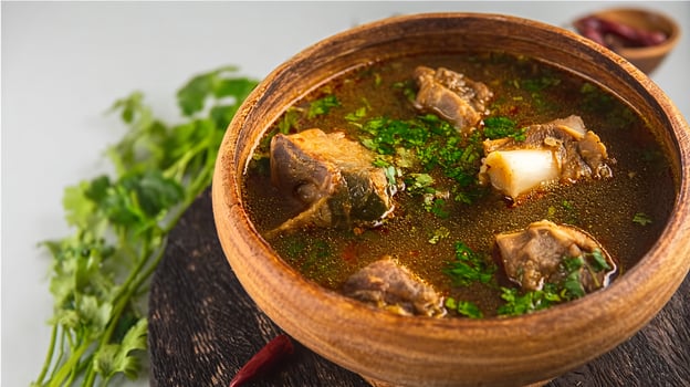Fresh spicy lamb paya soup in a wooden bowl and ready to eat. photo