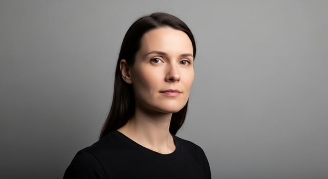 Portrait of a beautiful brunette woman with a serious expression, looking directly at the viewer with a clean, modern aesthetic against a neutral grey background. photo