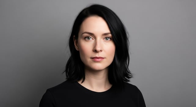Confident woman with dark hair and a neutral expression looking directly at the camera, isolated on a clean grey studio background. photo