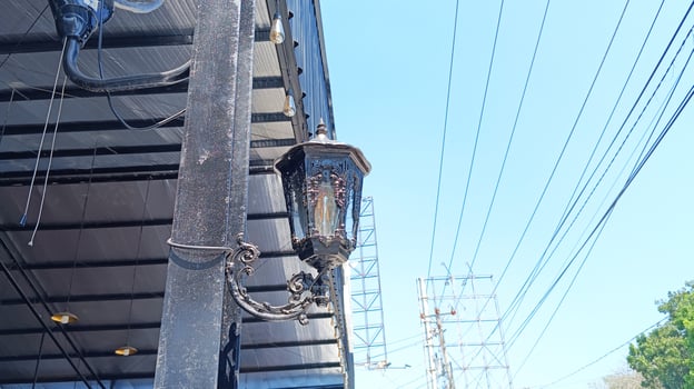 An electric pole with several electric cables attached, as well as a black hanging street light. photo