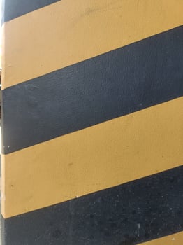 Image shows wall painted with alternating black and yellow diagonal stripes, creating bold and striking pattern that emphasizes safety or caution photo