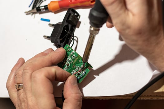 man solders wiring in the electronic circuit board of the device. photo