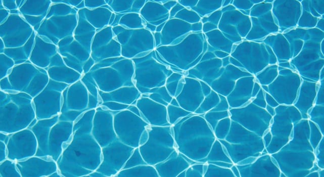 Sunlight reflecting on the surface of a clear blue swimming pool photo
