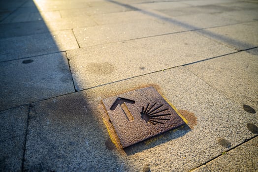 A metal pilgrim marker embedded in a stone sidewalk in Spain. Ancient Pilgrim Route photo