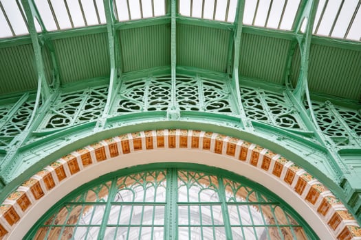 Green metal and glass structure forming an arch in a building photo