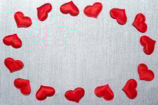 red hearts laid out in the shape of an oval on a silver background photo