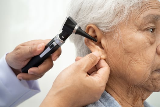 Otolaryngologist or ENT physician doctor examining senior patient ear with otoscope hearing loss photo