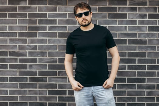 Adult stylish man with a beard in a black T-shirt and glasses, Street photo. photo