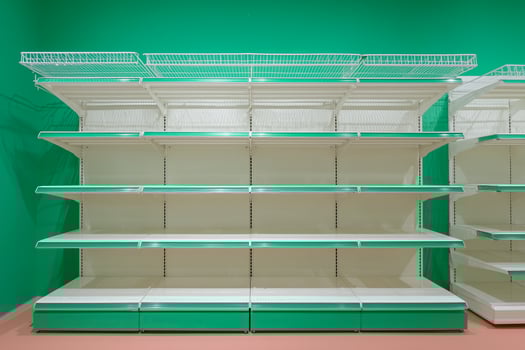 The image features a row of empty white metal shelves with green accents, set against a vibrant green wall. The shelves are neatly arranged, showcasing their emptiness. photo