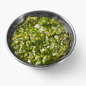 Fresh pesto sauce with olive oil in a small bowl on white background photo