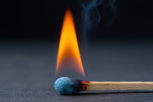 Matchstick with blue head ignites in vertical frame photo