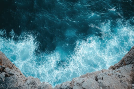 The ocean is seen from above with waves crashing into the rocks photo