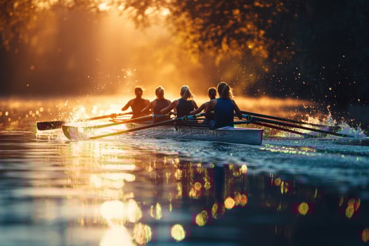 A group of people rowing on a river at sunset photo