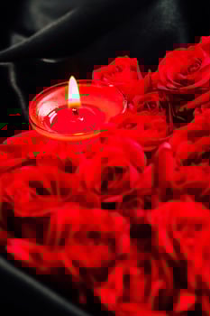 Romantic setting with red roses and a lit candle on a dark background in an intimate setting photo