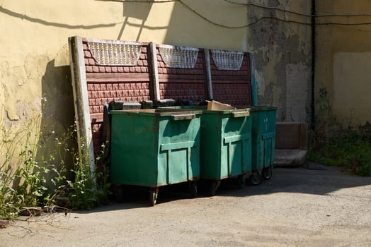 A vibrant urban scene shows green dumpsters in a cluttered alley, embodying city life photo