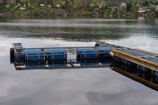 Floating metal dock with blue barrels on calm lake water - industrial waterfront platform structure photo