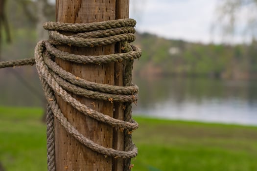 Closeup of weathered rope wrapped around wooden post by lake in Nova Zivohost, Czech Republic photo